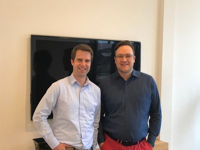 Zwei Mitarbeiter von Wegner Immobilien lächeln vor einem Bildschirm – Teambildung