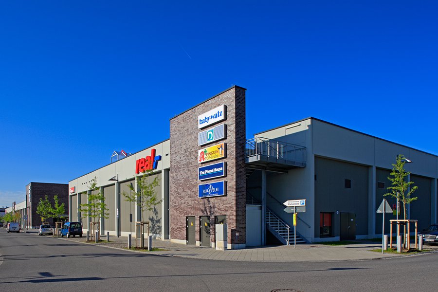 Marktgebäude mit Logos von real, Rossmann und anderen