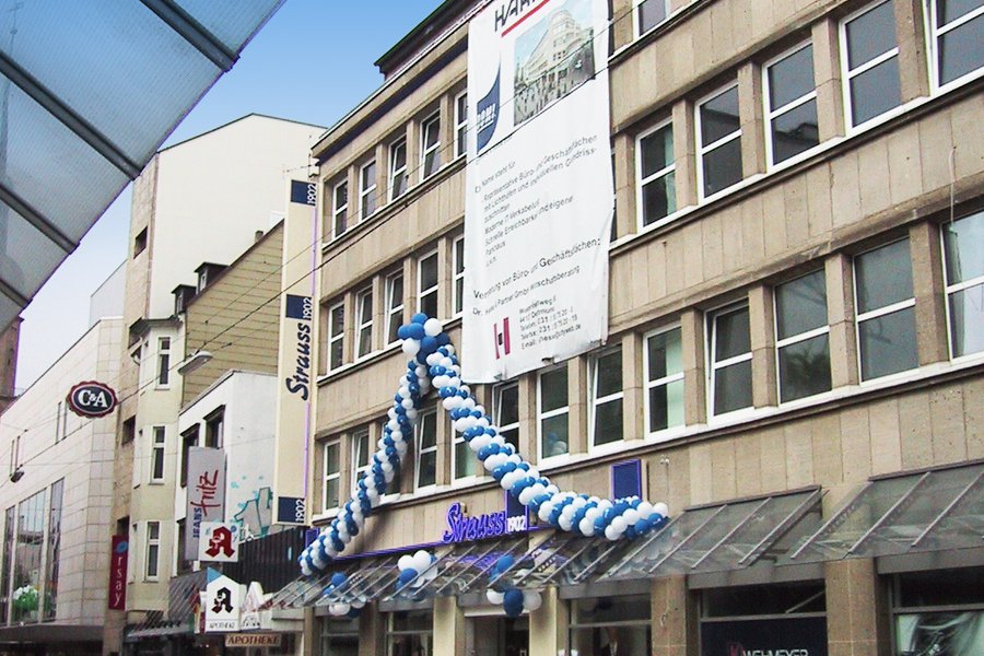 Eingangsfassade mit Schriftzug Strauss und blauer Luftballon-Deko