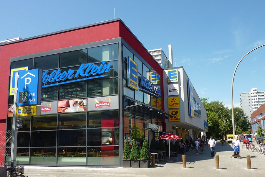 Eingang mit Glasfassade und Kunden vor dem Markt