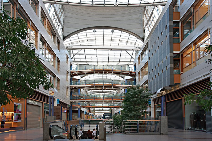 Ladenpassage im Atrium mit Glasdach und Pflanzen