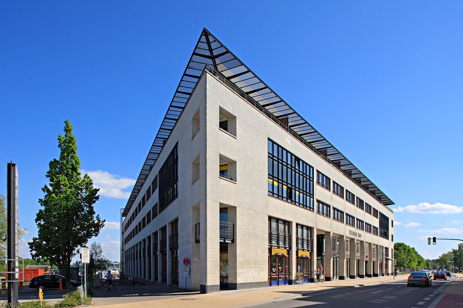 Außenansicht des Eckgebäudes mit Glas- und Steinfassade